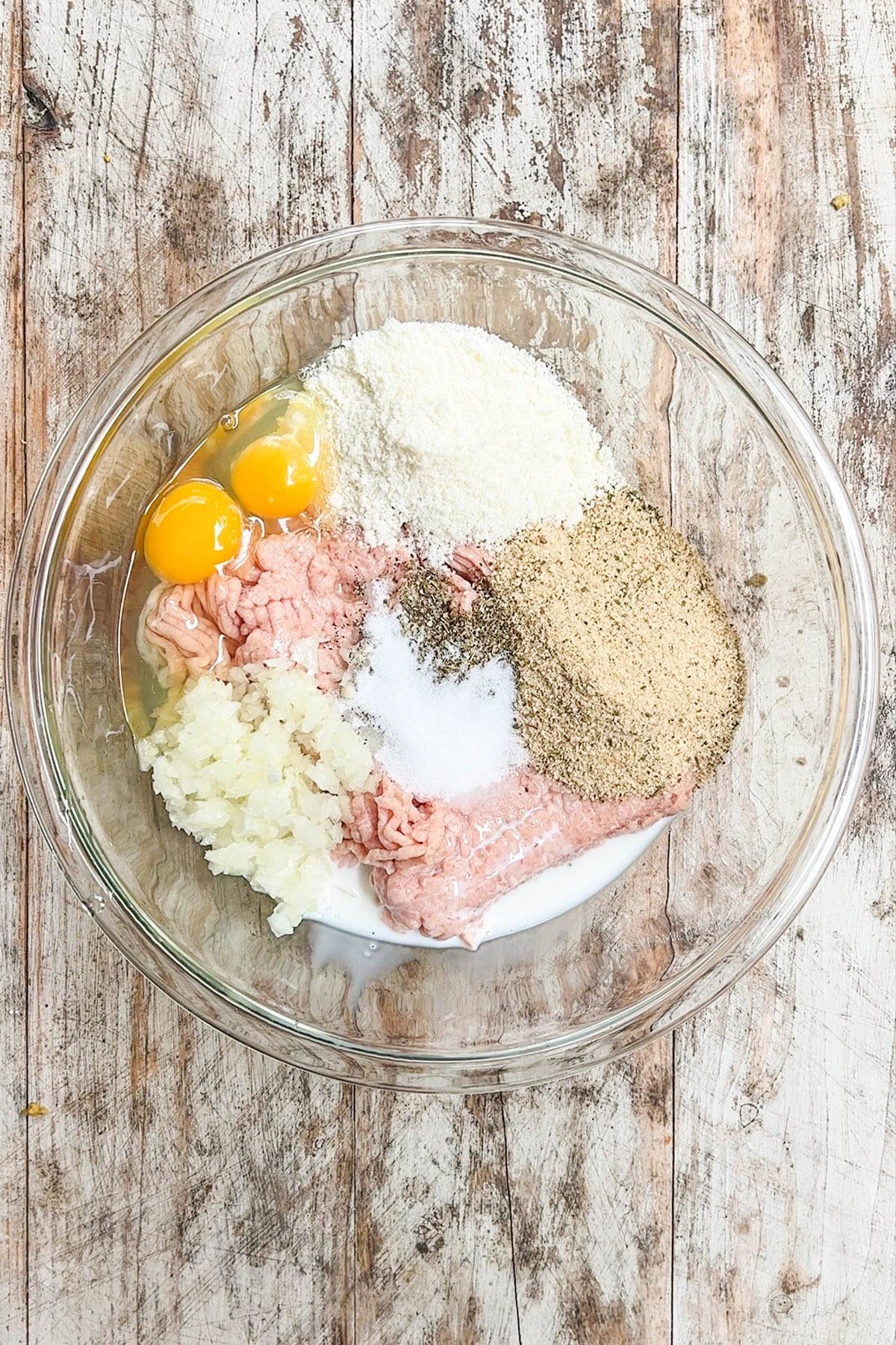 Ingredients for Chicken Parmesan Meatloaf Muffins in a bowl, ready to be mixed.