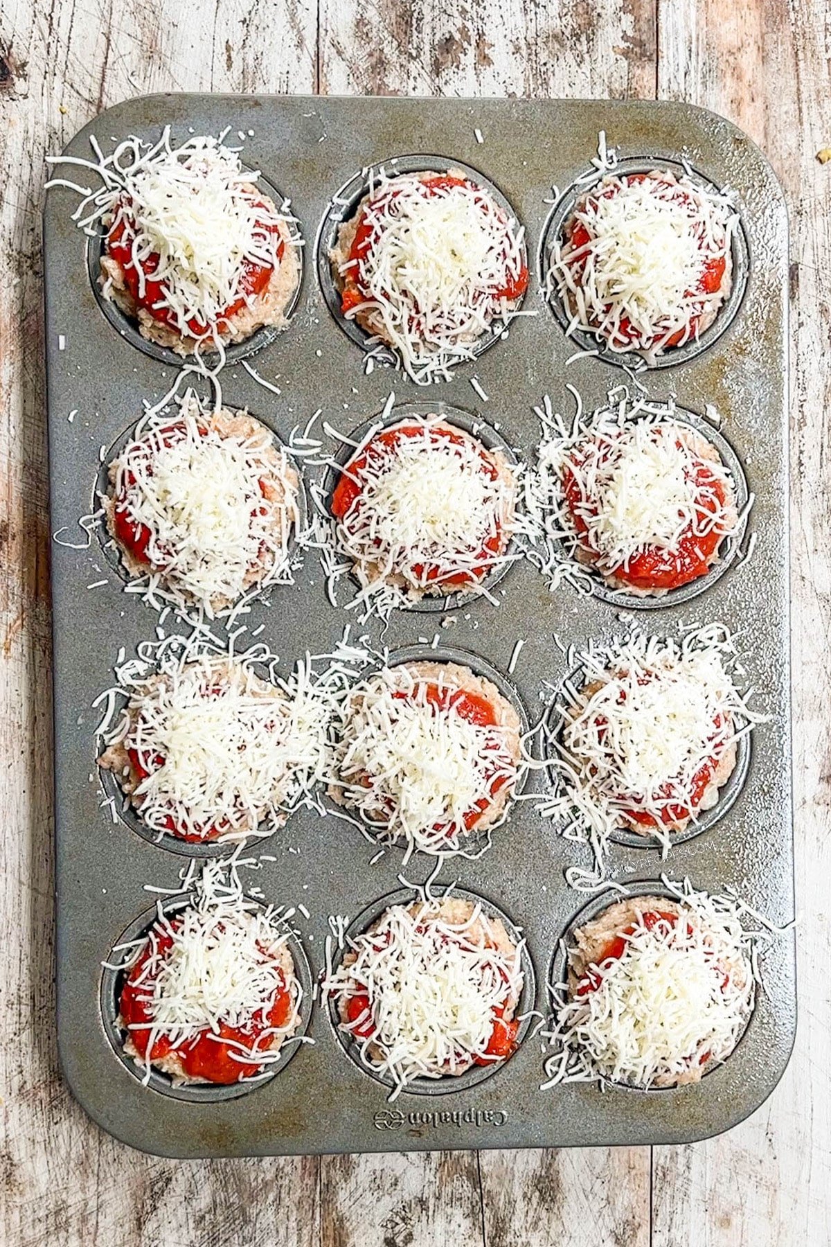 Chicken Parmesan Meatloaf Muffins in a muffin tin, ready to bake.