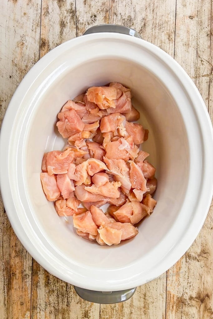 raw chicken pieces in a crockpot.