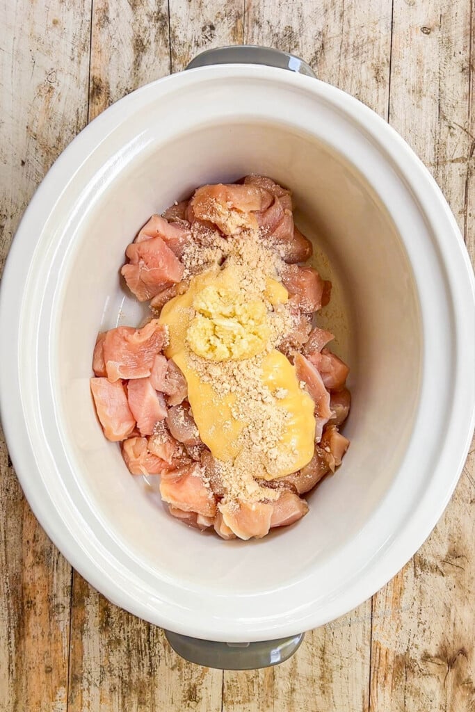 chicken pieces layered with cream of chicken soup in a slow cooker.