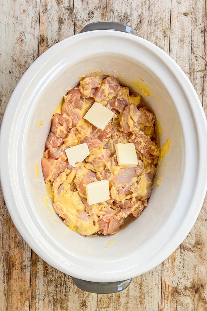 chicken topped with pats of butter in the slow cooker.