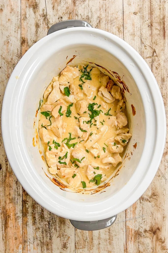 above image of a crockpot filled with finished creamy garlic chicken.