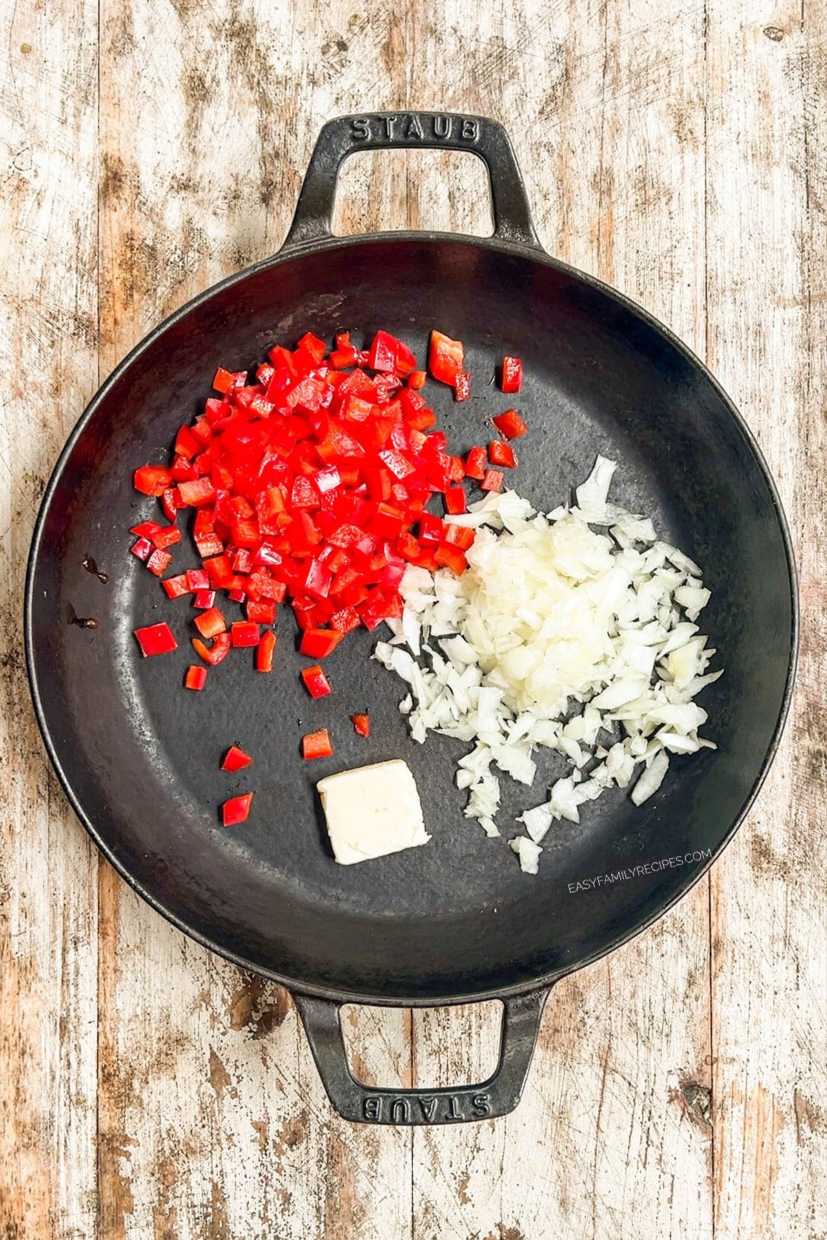 A black skillet with peppers and onions about to be sautéed for Southwest Corn.