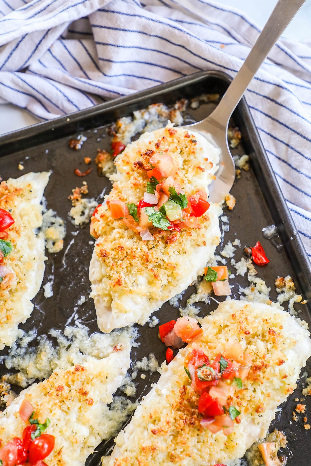 A sheet pan with Monterey Jack Unfried Chicken, ready to serve. A blue and white striped towel is in the background.