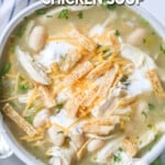 A white bowl full of Salsa Verde Chicken Soup with cheese and chips on top. A lime and cilantro are scattered in the background. The text reads, "Salsa Verde Chicken Soup."