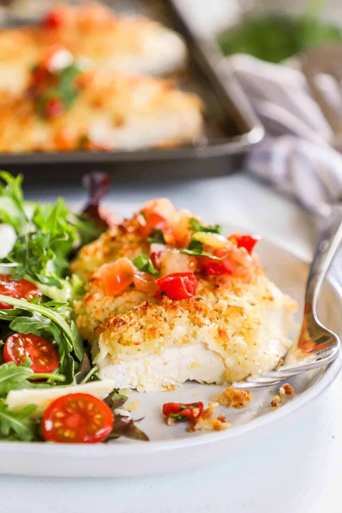 Monterey Jack Unfried Chicken on a white plate with a side salad next to it.