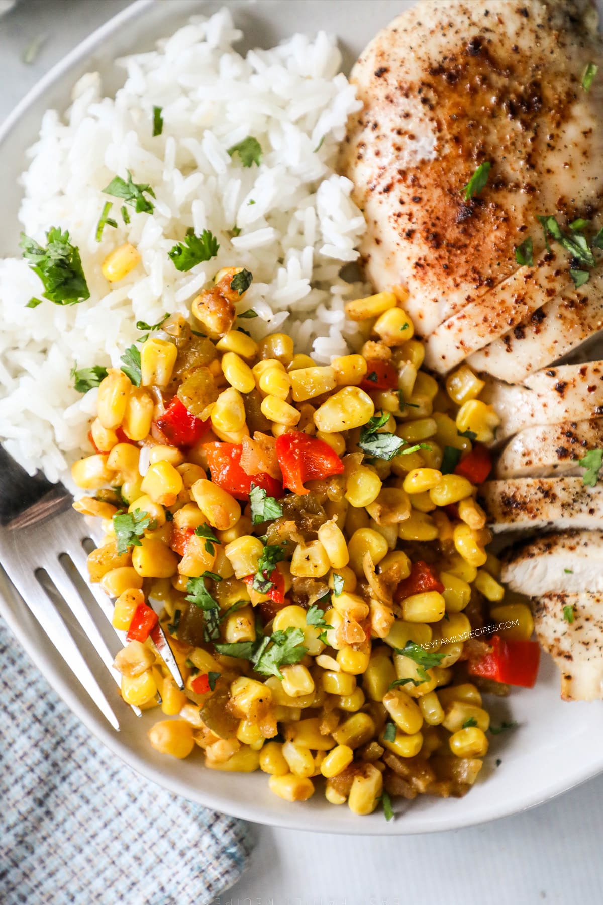 Southwest Corn on a white plate with chicken breast and rice.