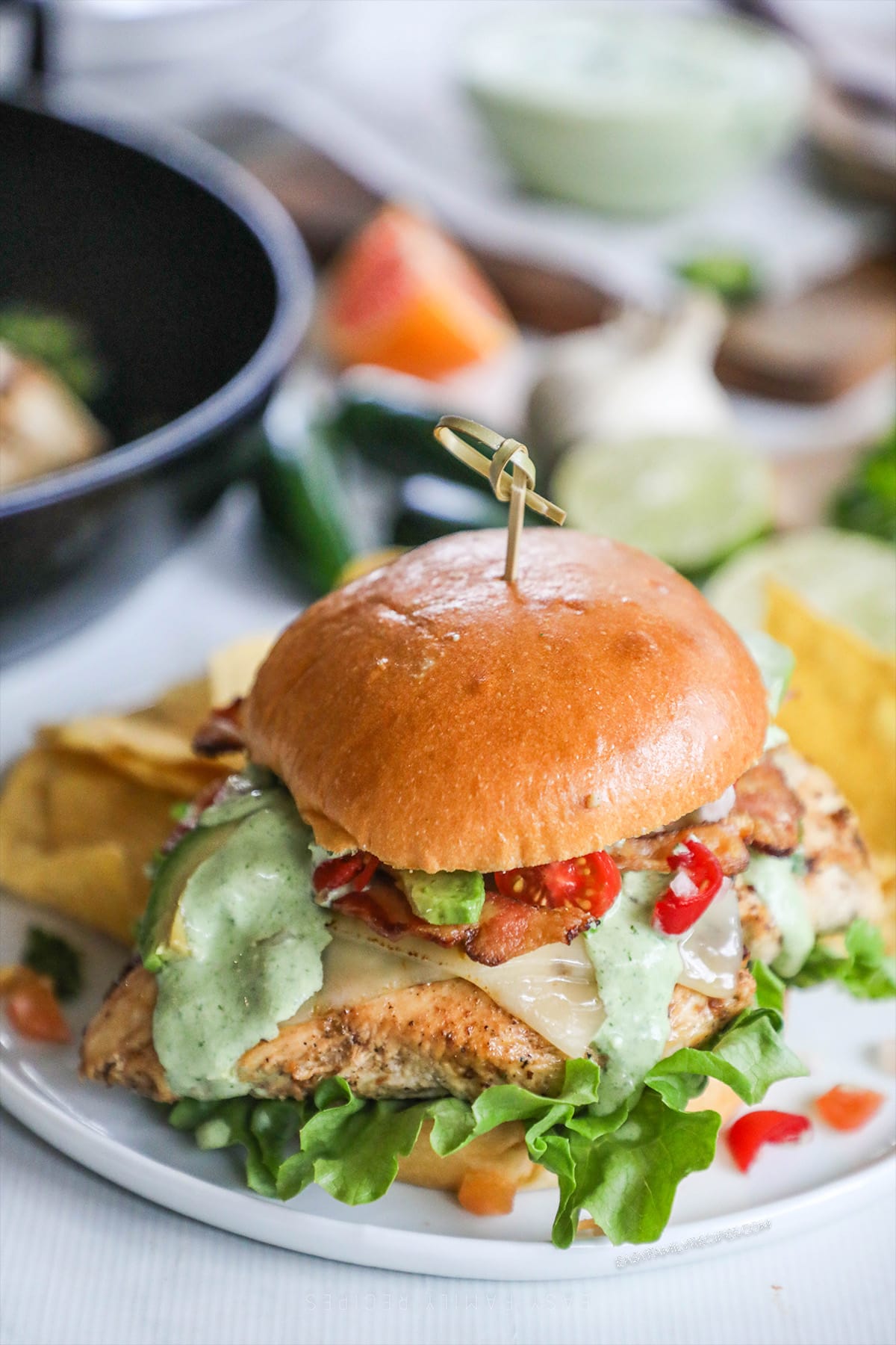 Baja Chicken Sandwich on a white plate with a skillet and ingredients in the background. 