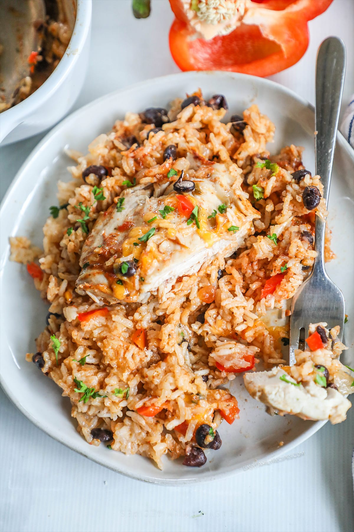 A serving of Mexican Chicken and Rice Bake on a white plate with a silver fork.