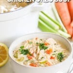 A bowlful of lemon chicken orzo soup in a white bowl with a white Dutch oven full of the soup in the background. A lemon half, carrots, and celery are in the background. The text reads, "Creamy Lemon Chicken Orzo Soup."