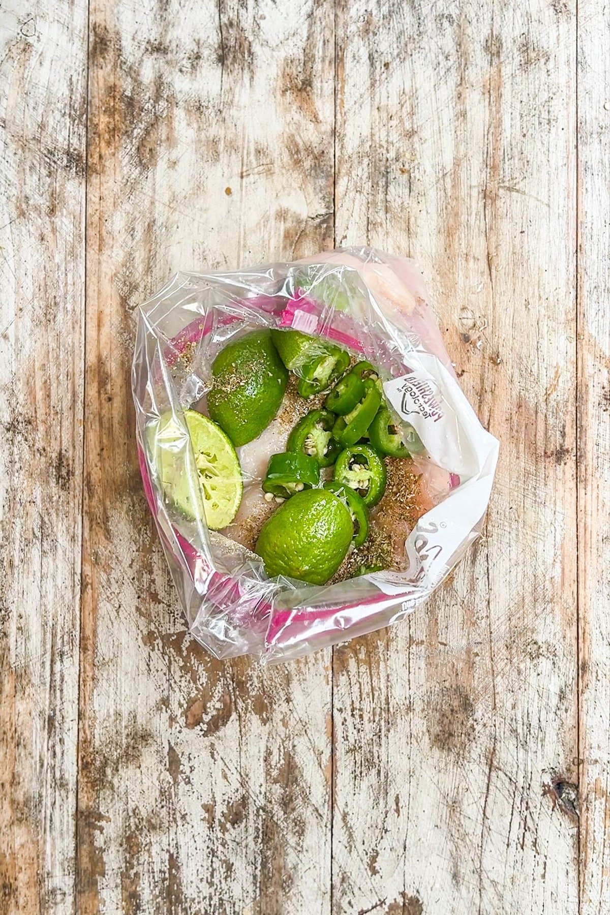 Citrus and jalapeños are added to chicken in a zipper bag, step 2 for making Baja Chicken Sandwiches.