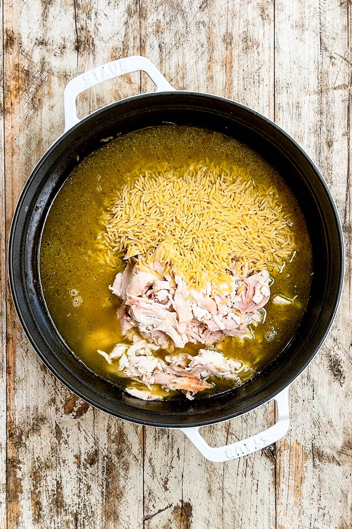 Broth, orzo, and chicken are added to the Dutch oven for Creamy Lemon Chicken Orzo Soup.