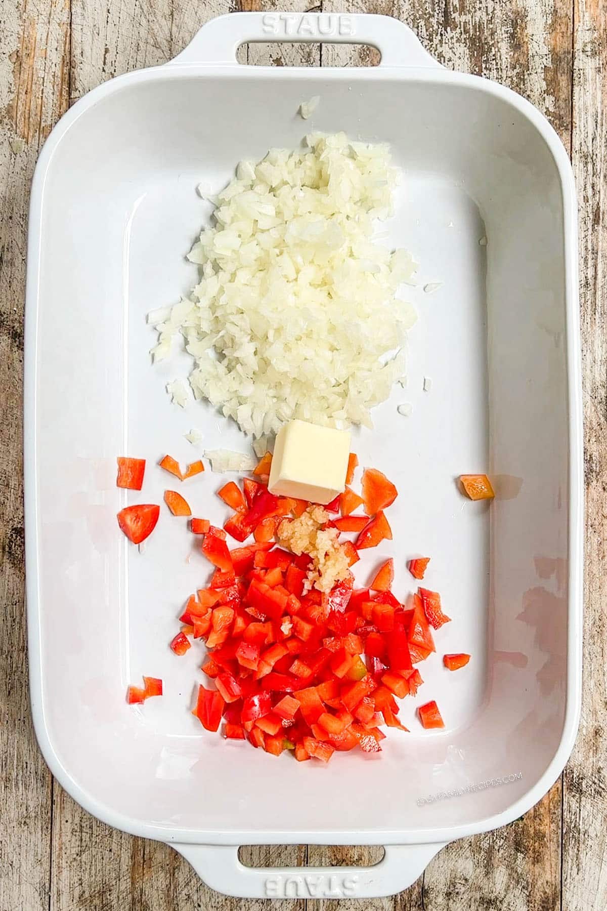 Step 1 of how to make Mexican Chicken & Rice Bake: Veggies and butter are added to the baking dish.