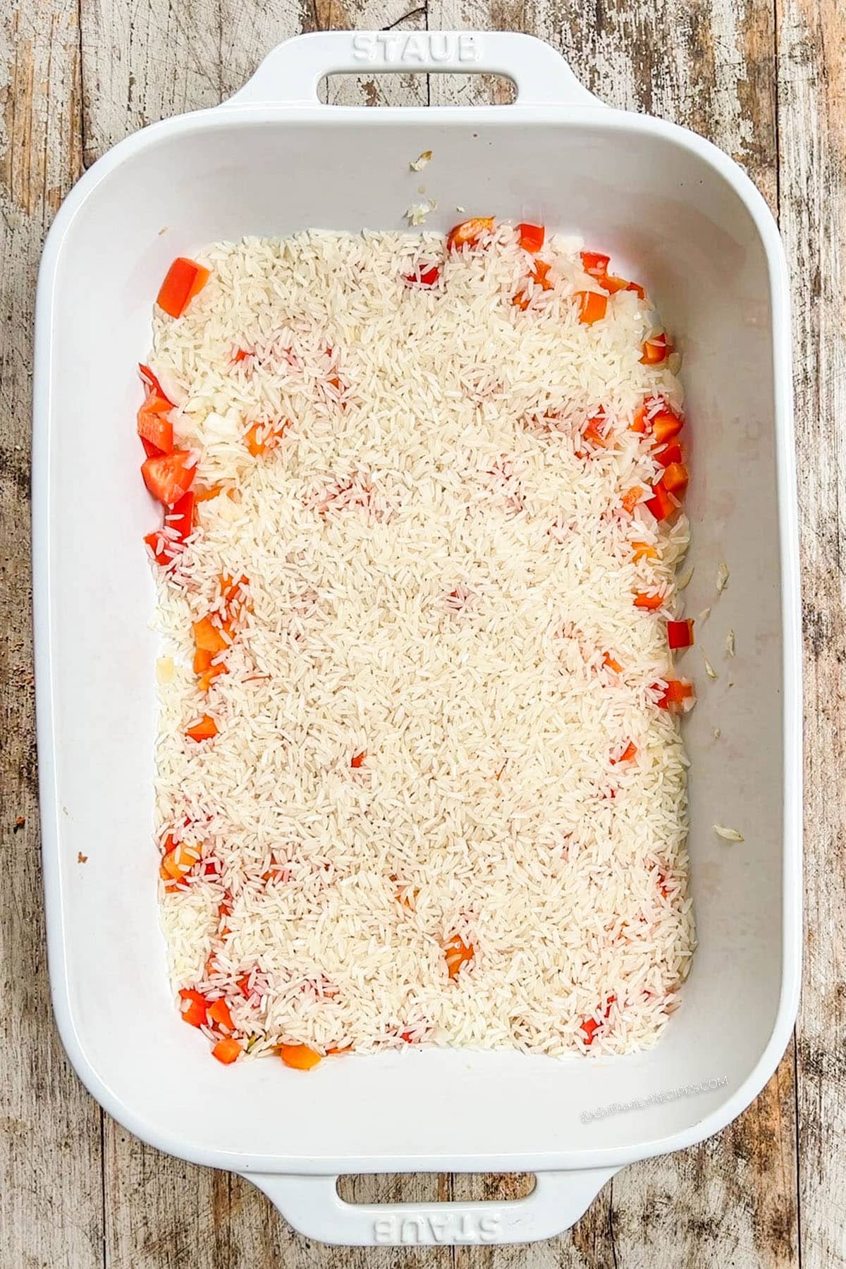 Step 2 of how to make Mexican Chicken & Rice Bake: Long grain rice is added to the casserole dish.