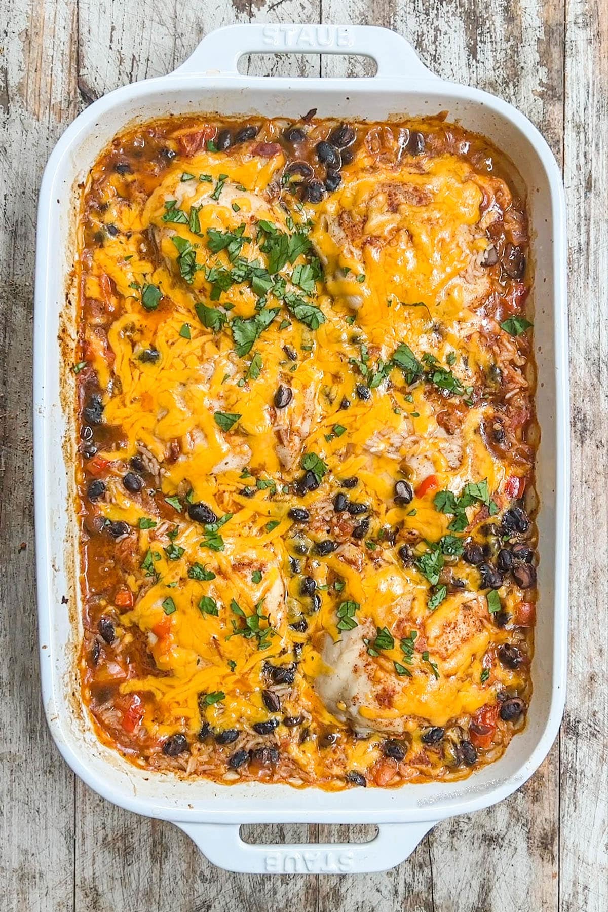 A top view of cheesy Mexican chicken and rice in a white baking dish.