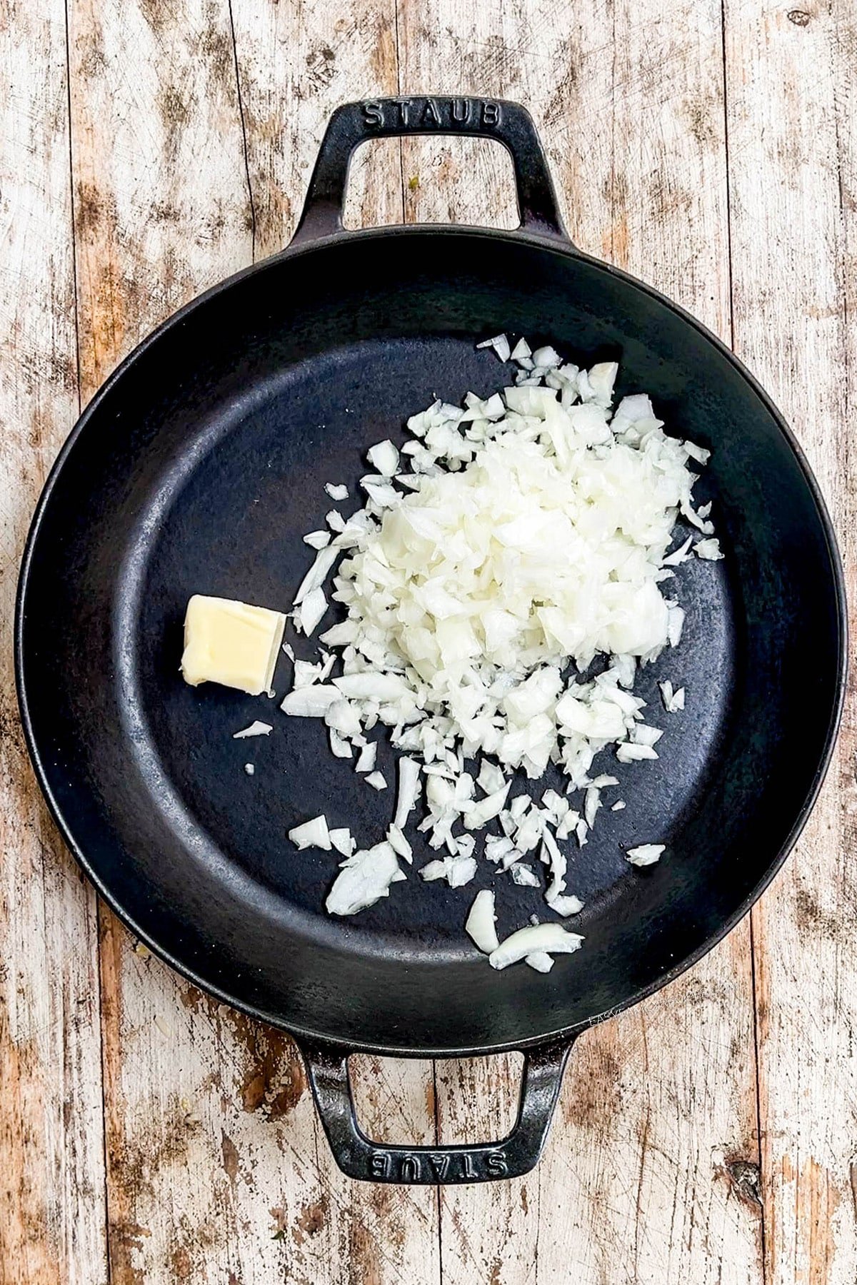 Onion and butter are added to a skillet for vegetable fried rice.