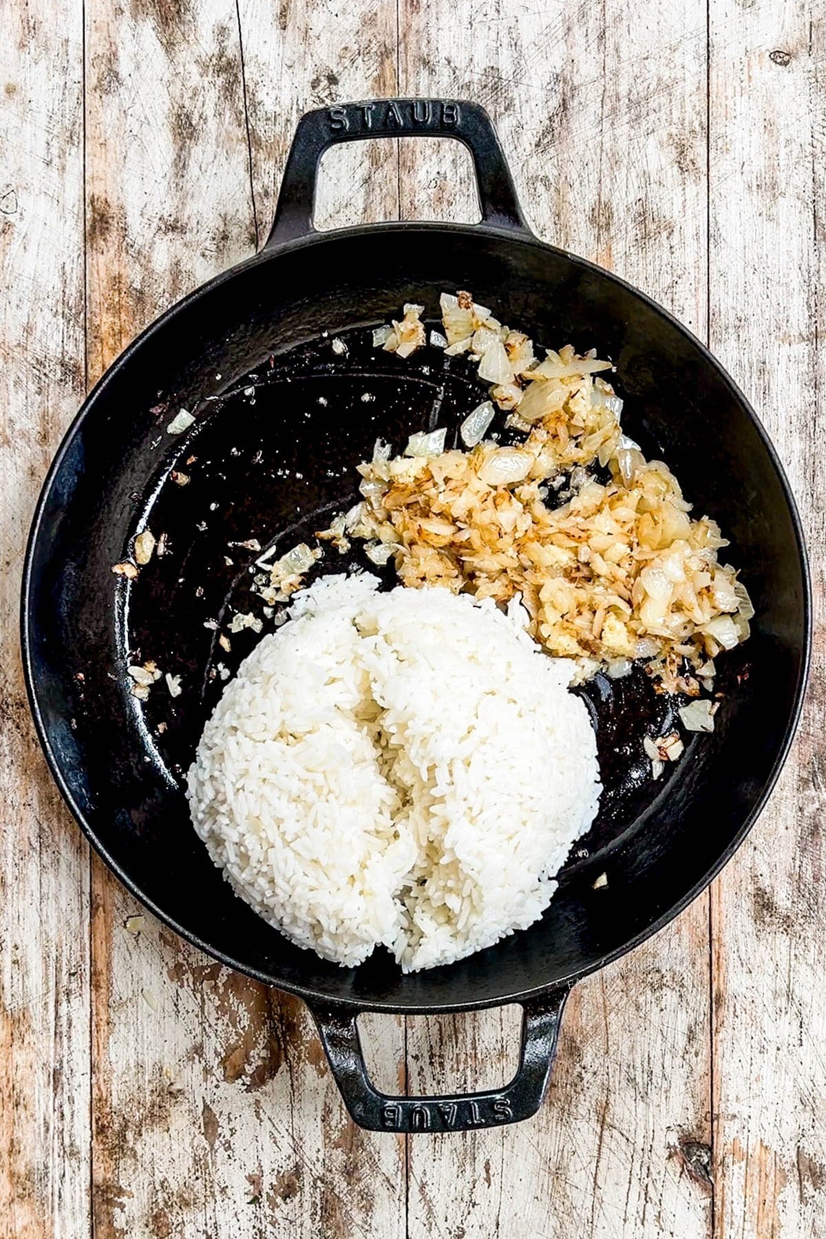 Cooked rice is added to a skillet for vegetable fried rice.