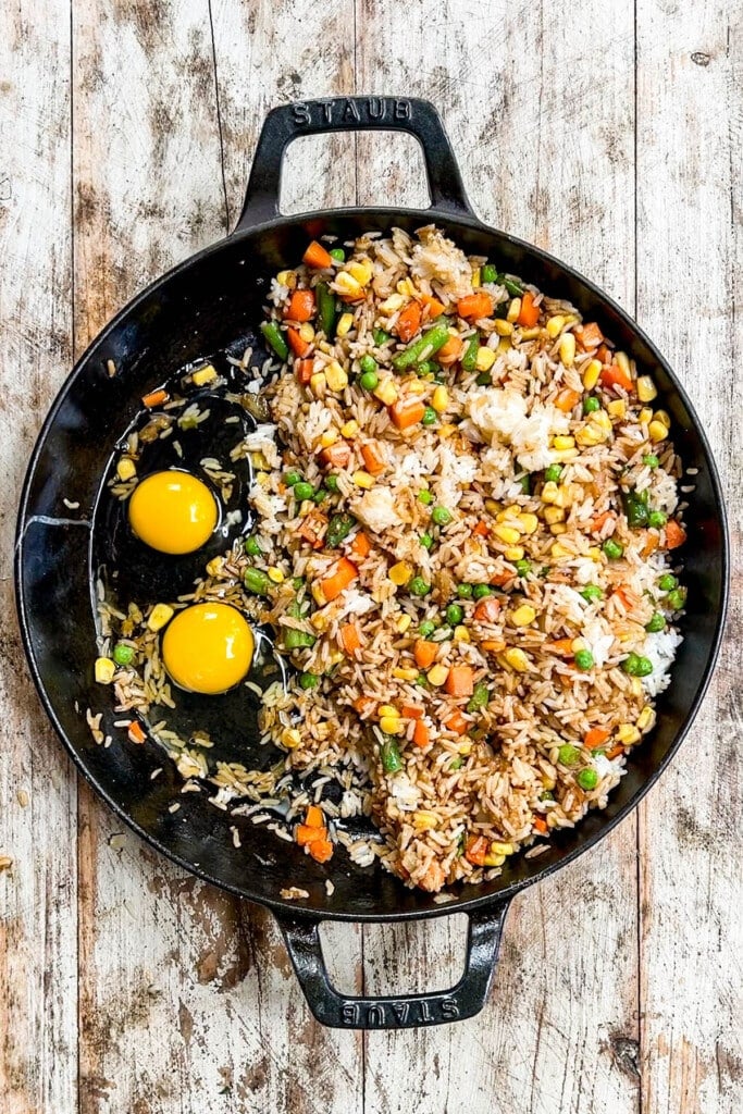 Egg is added to the skillet for vegetable fried rice.