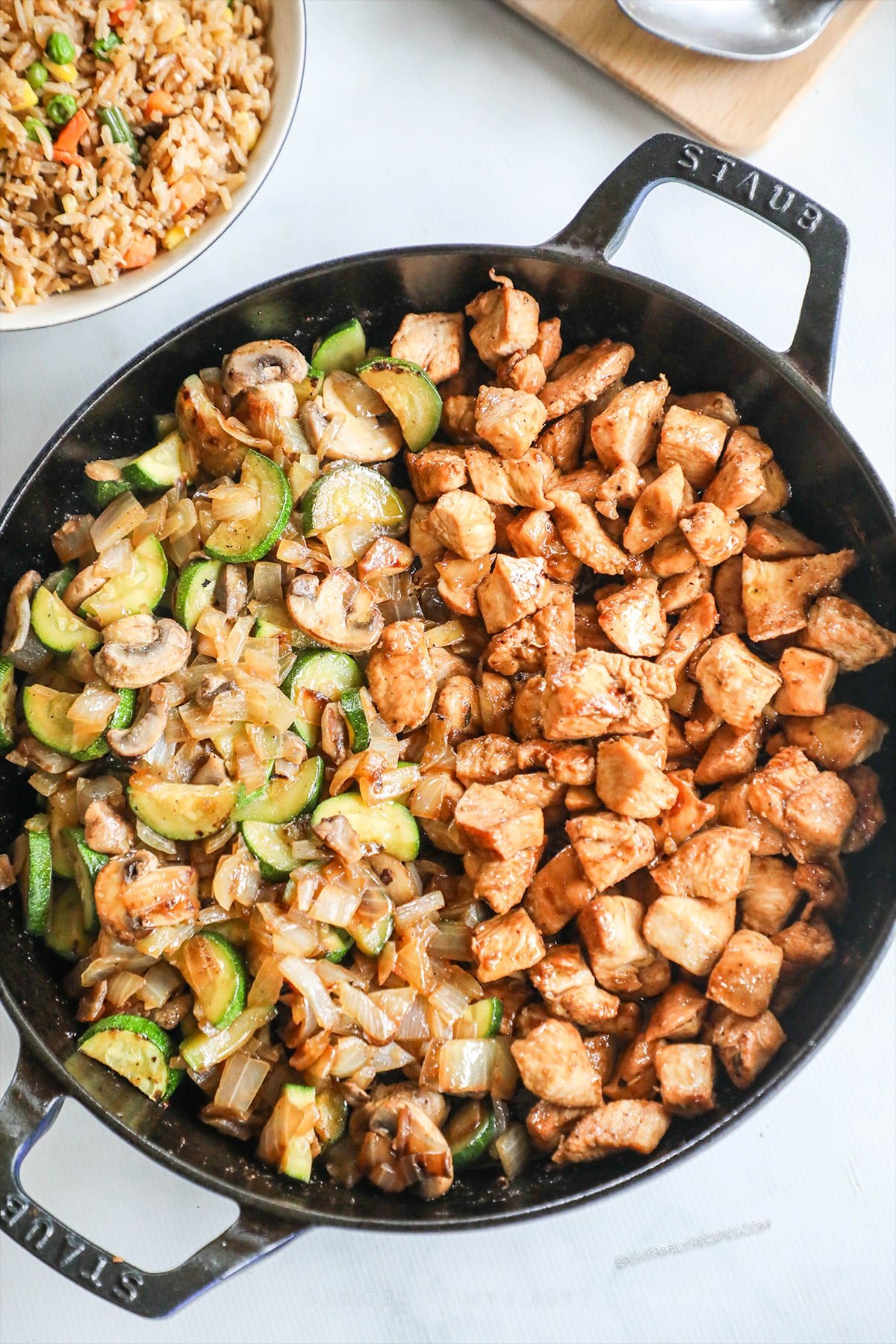 A top view of a black skillet full of Hibachi Chicken and Vegetables on a white background.