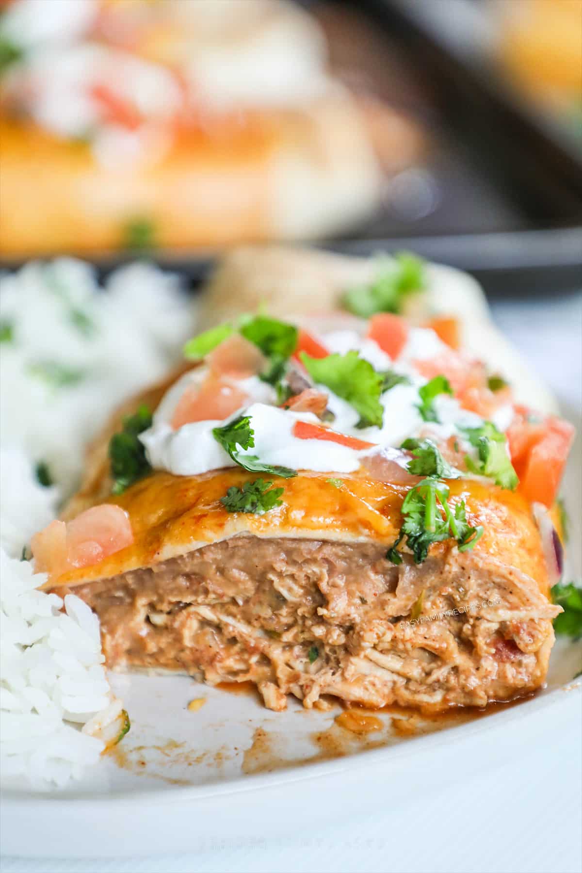 Half of a chimichanga on a white plate with rice.