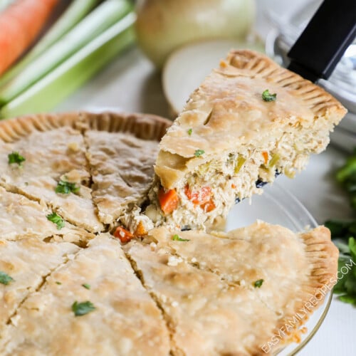 A slice of chicken pot pie is lifted from a glass pie dish.