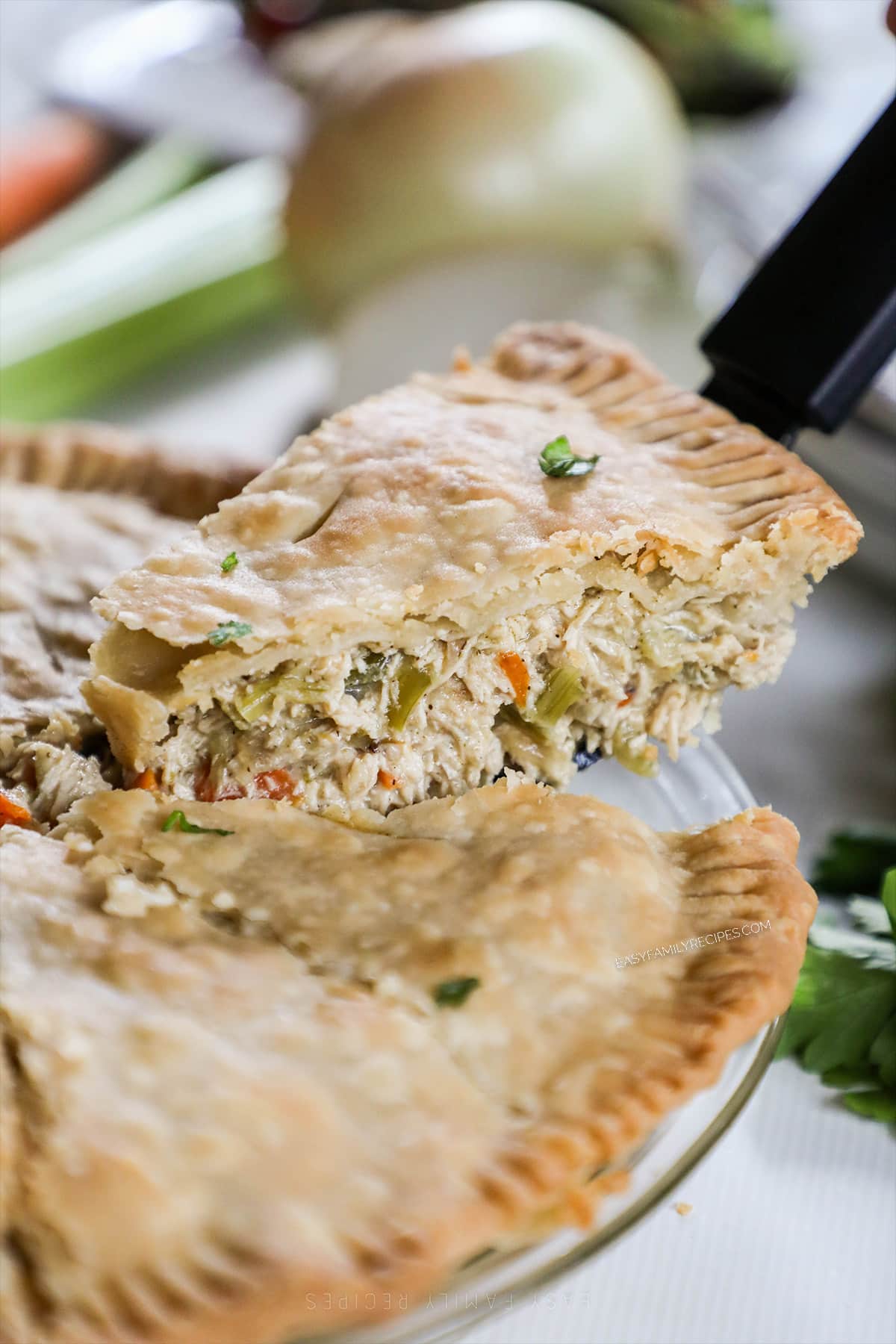 A slice of chicken pot pie is lifted from a glass pie dish.