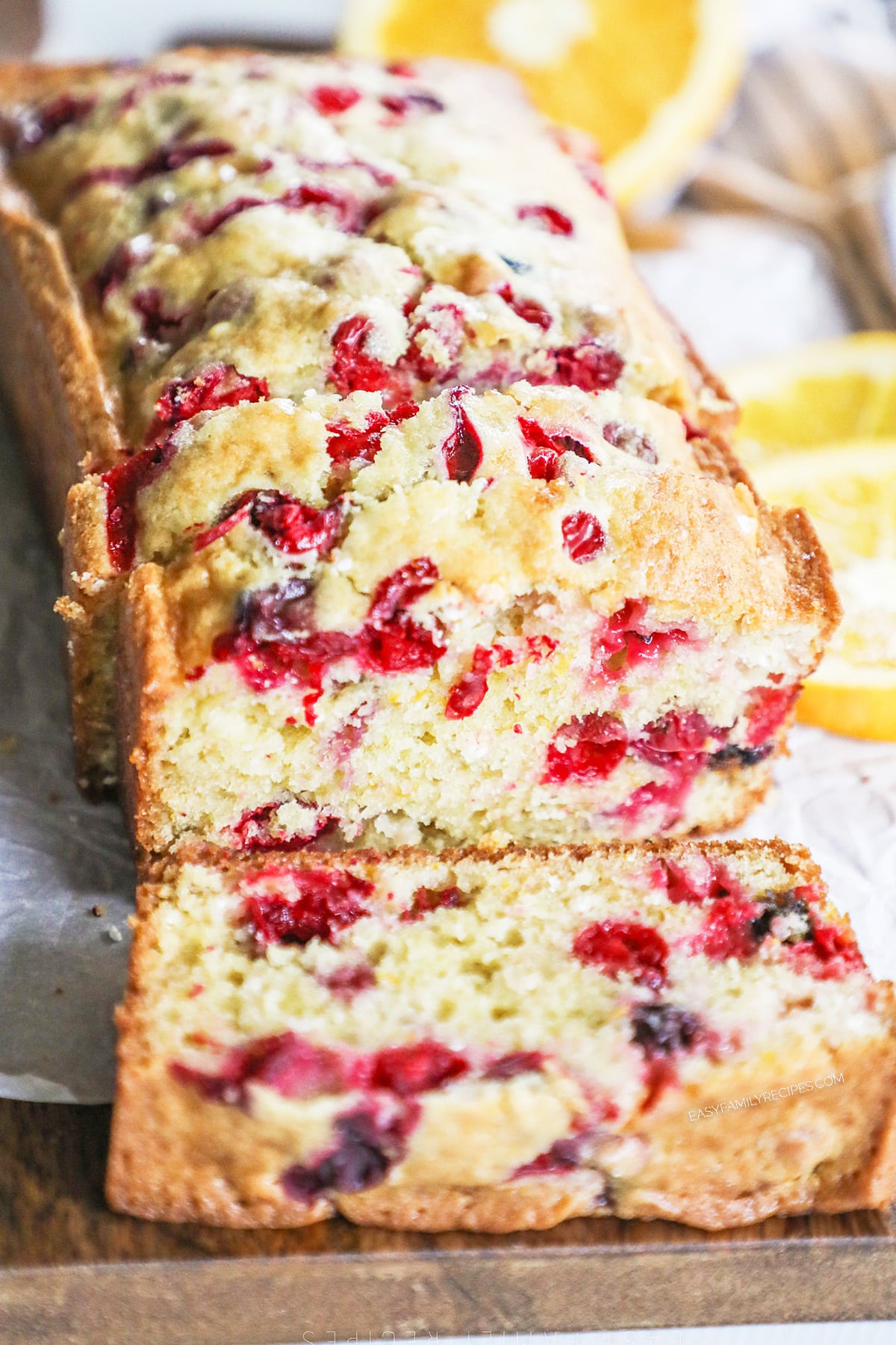 a loaf of cranberry orange bread with a slice cut off. 