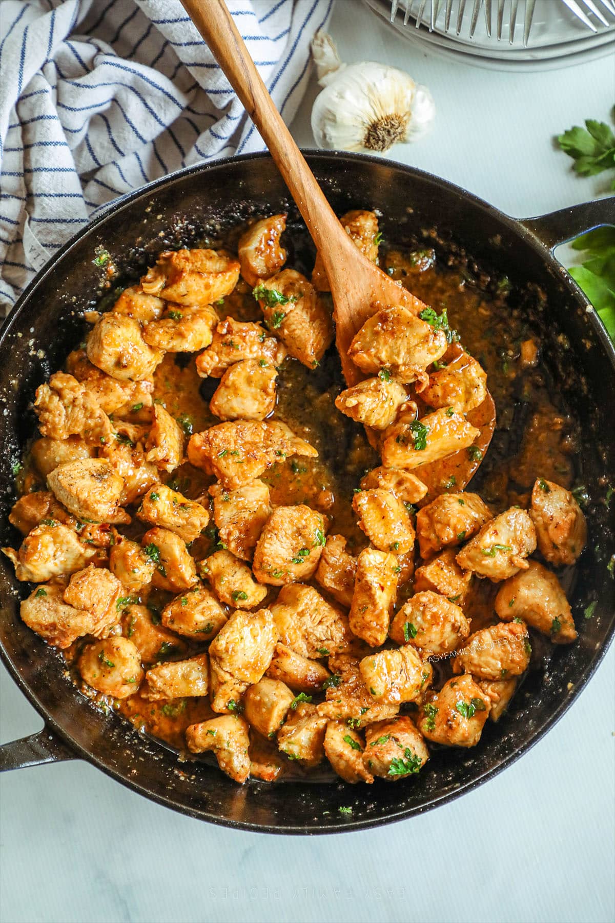 Garlic Butter Chicken Bites in a black skillet with a wooden spoon in it. 