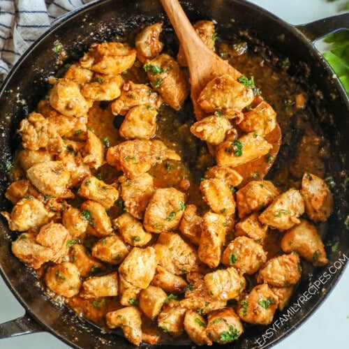 Garlic Butter Chicken Bites in a black skillet with a wooden spoon in it.