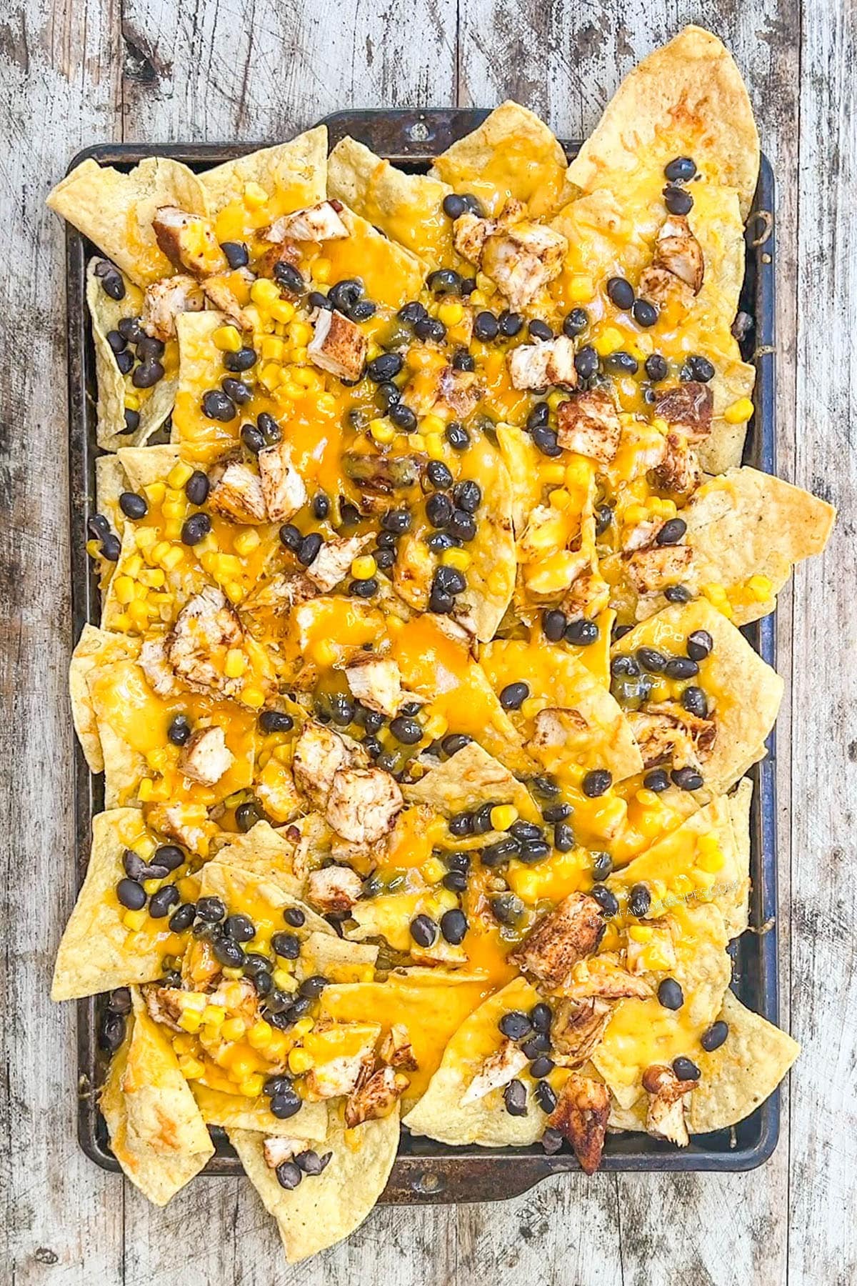 BBQ chicken nachos fresh out of the oven and ready for toppings, step 5 of how to make BBQ chicken nachos.