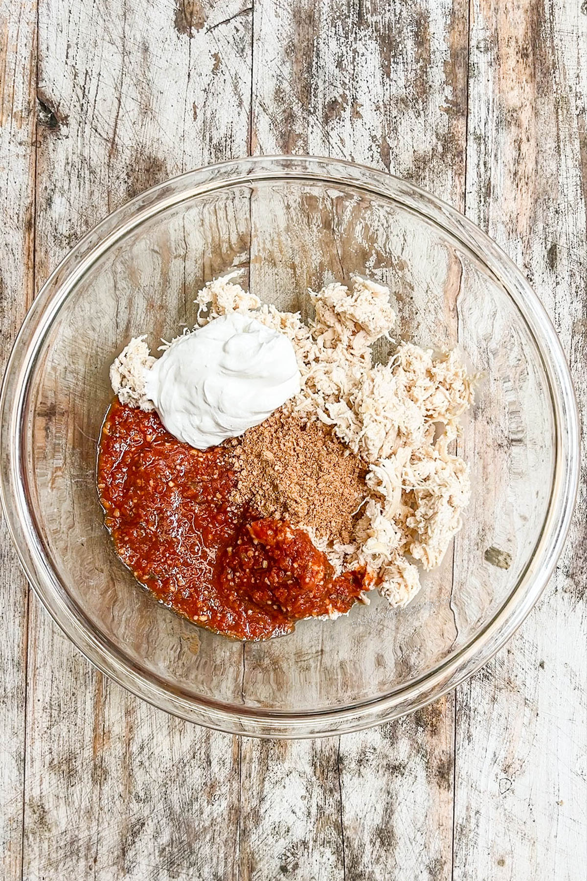 Step 1 of making chimichangas: The filling ingredients are added to a clear glass bowl.