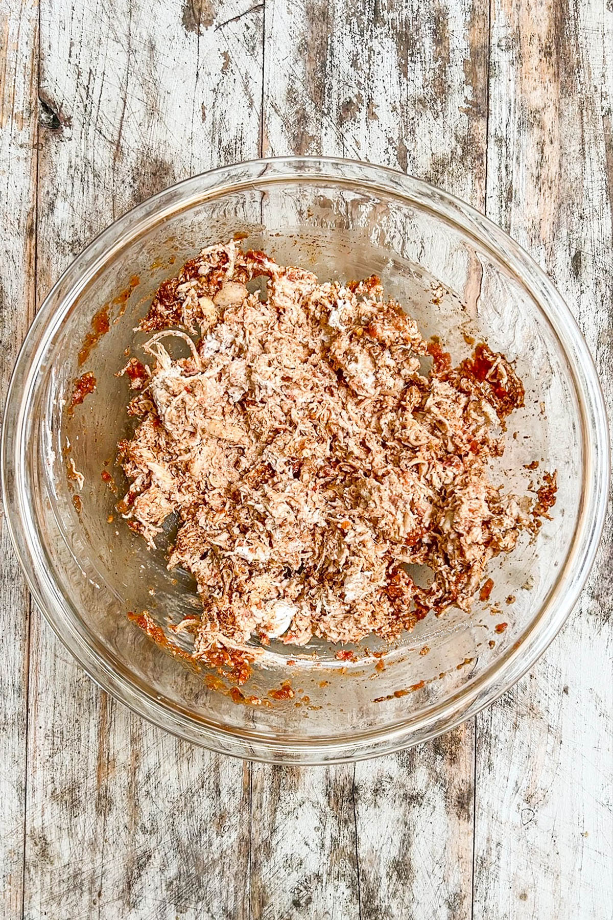 Step 2 of making chimichangas: The filling ingredients are mixed together in a clear glass bowl.