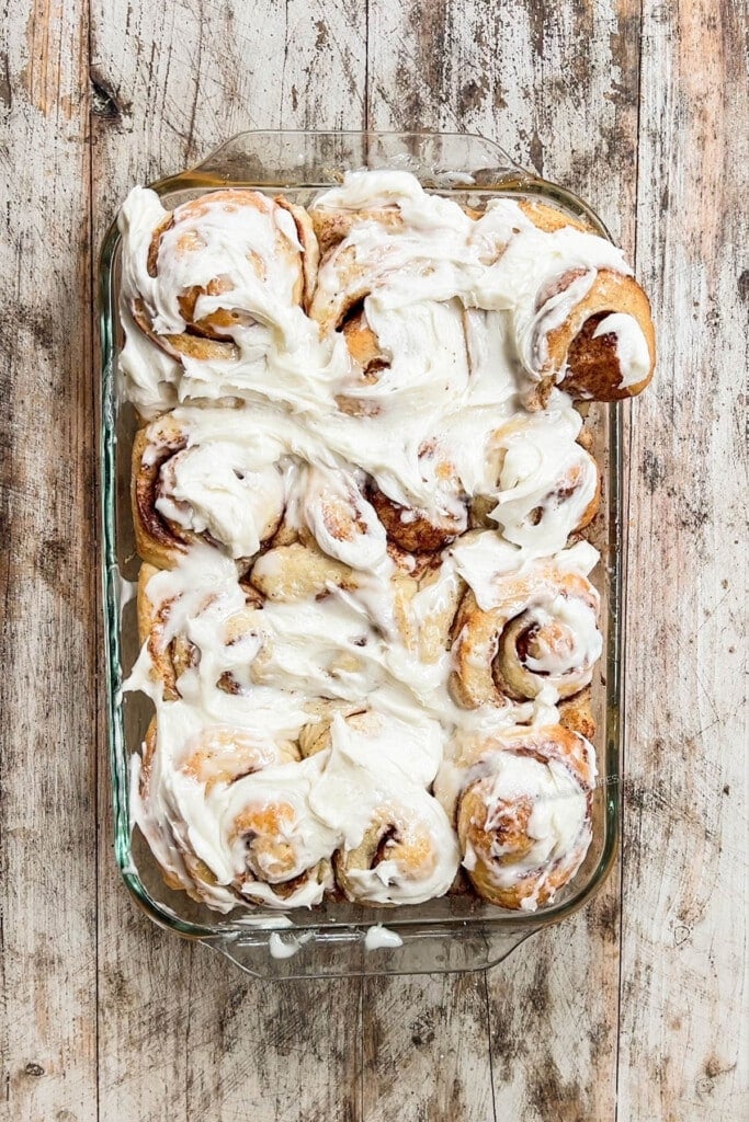 above image of a baking pan filled with frosted cinnamon rolls.