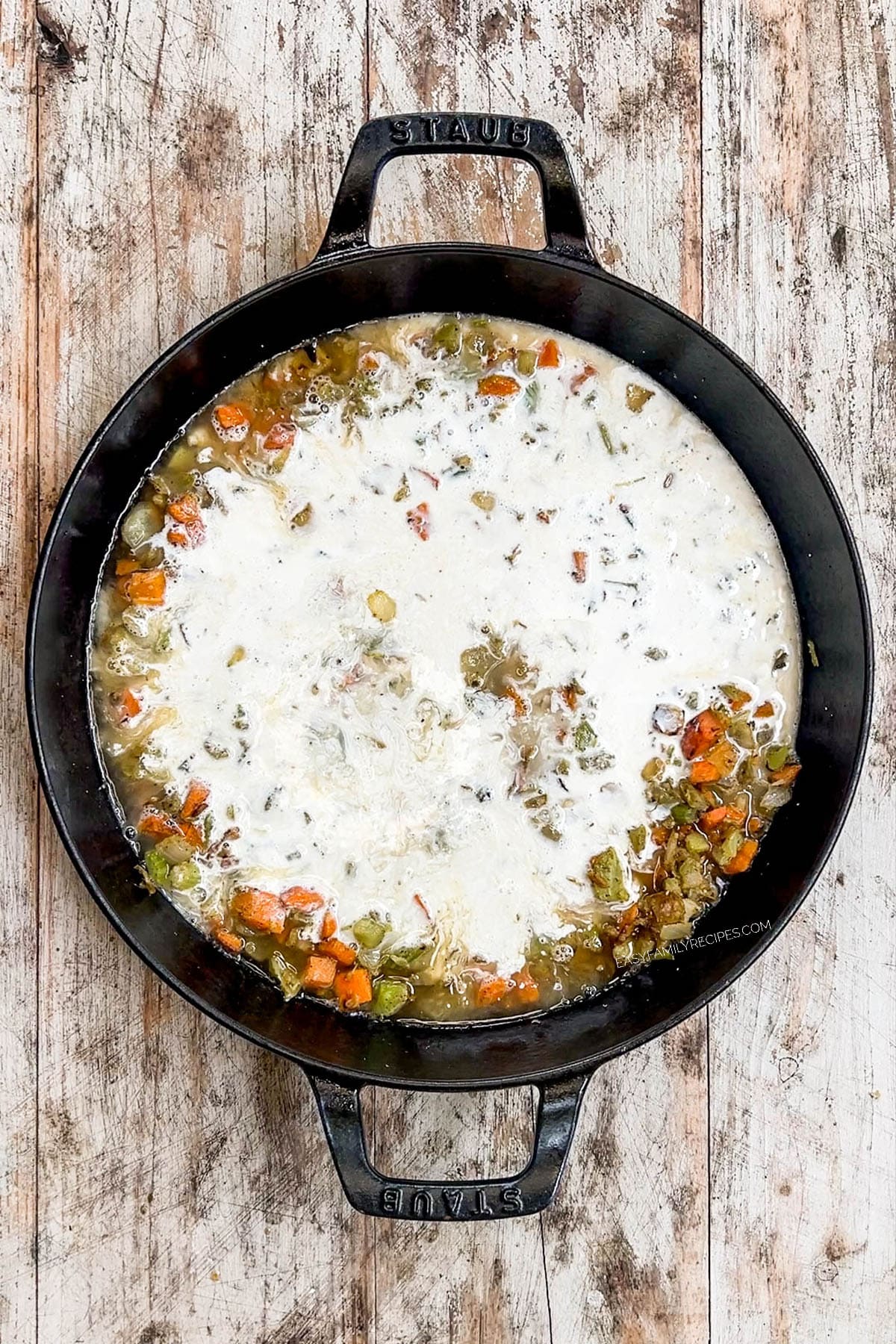 Step 3 of making chicken pot pie - cream is added to the veggies in the skillet.