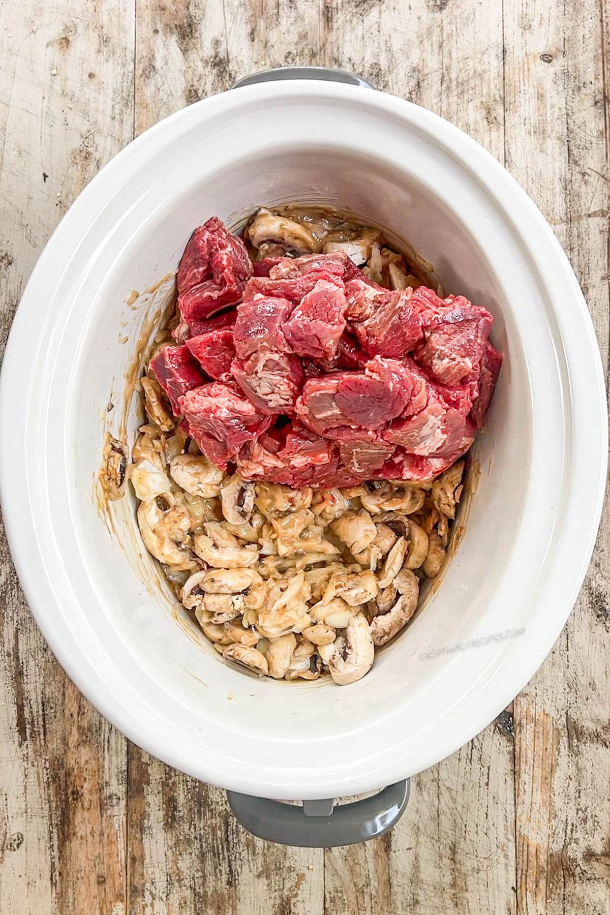 Stew meat is added to the Crock Pot, step 3 in making slow cooker stroganoff.