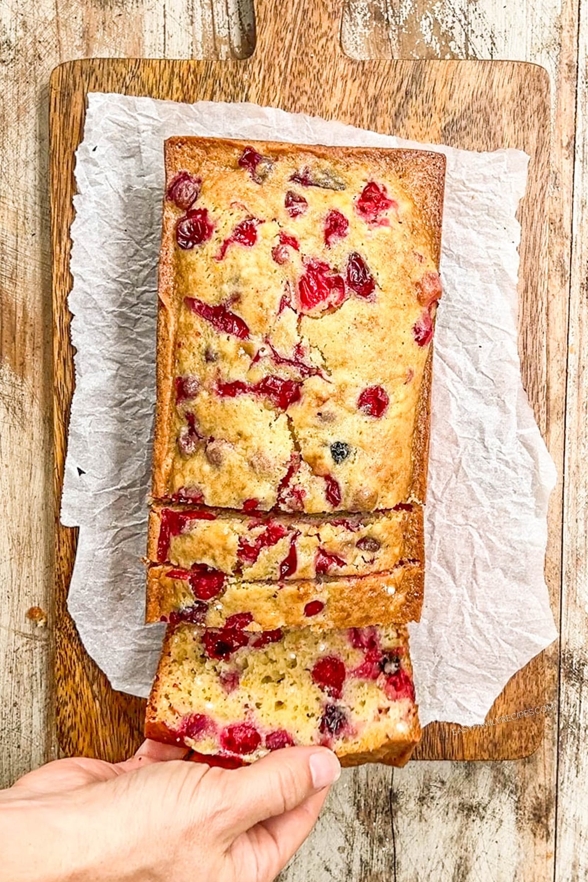 above image of a loaf of cranberry orange bread on a cutting board.