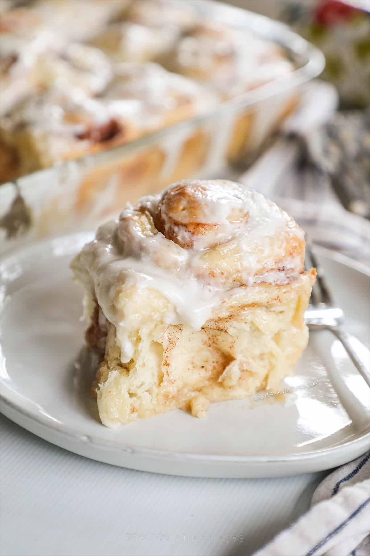 a cinnamon roll on a plate from the side. 