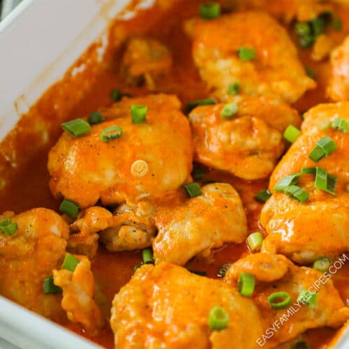 A white casserole dish full of Baked Buffalo Chicken Thighs