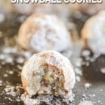 Cinnamon snowball cookies on a baking sheet, the first shows a bite out of it. The text reads, “Cinnamon Snowball Cookies.”