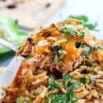 BBQ Shredded Chicken Casserole being lifted out of the casserole dish with a spoon to serve for an easy dinner.