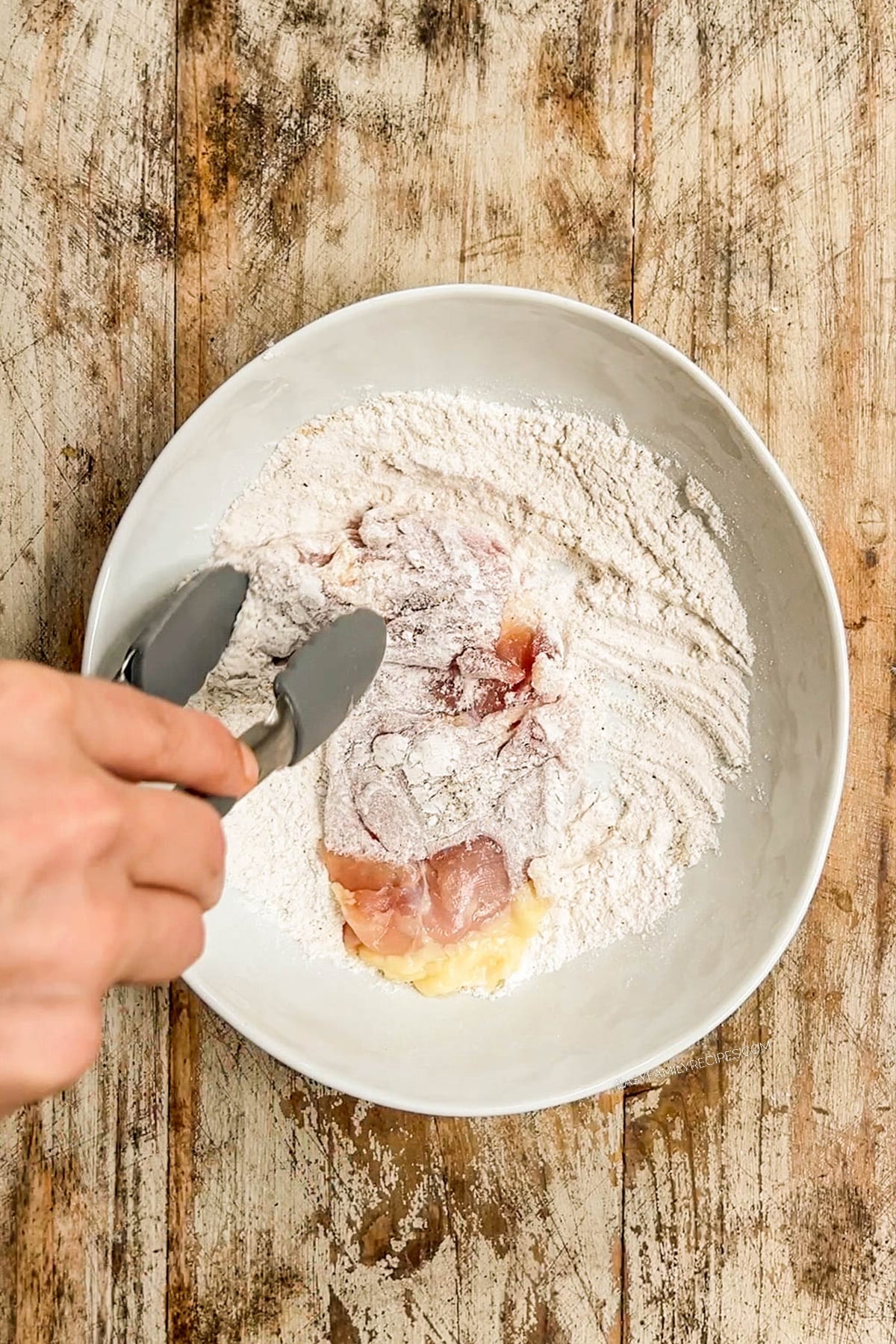 Chicken is tossed in flour and seasonings for baked buffalo chicken thighs.