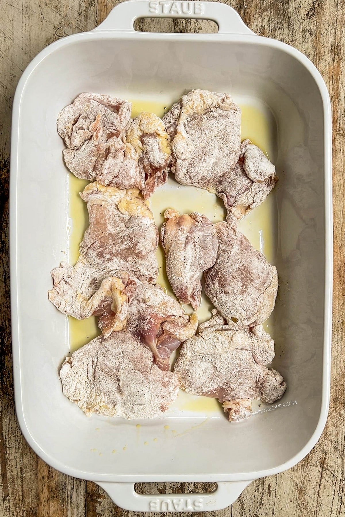 Chicken in a white baking dish, ready to bake for buffalo chicken thighs.