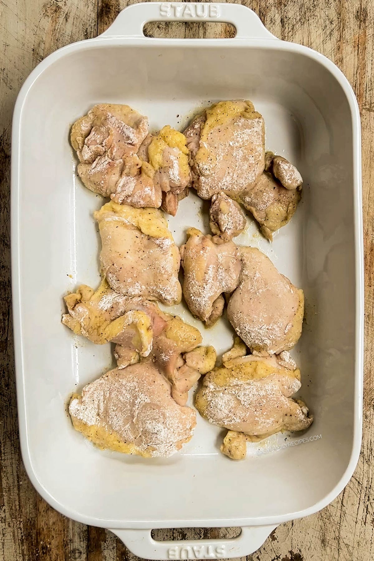 Baked chicken thighs in a white casserole dish, ready to be covered in sauce for baked buffalo chicken thighs.