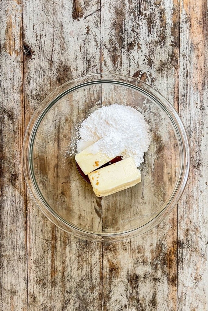 Step one to making Cinnamon Snowball Cookies - butter and sugar are added to a glass bowl.