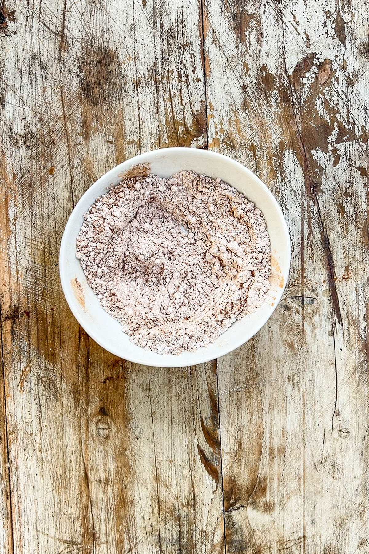 Cinnamon and powdered sugar are mixed together for cinnamon snowball cookies.