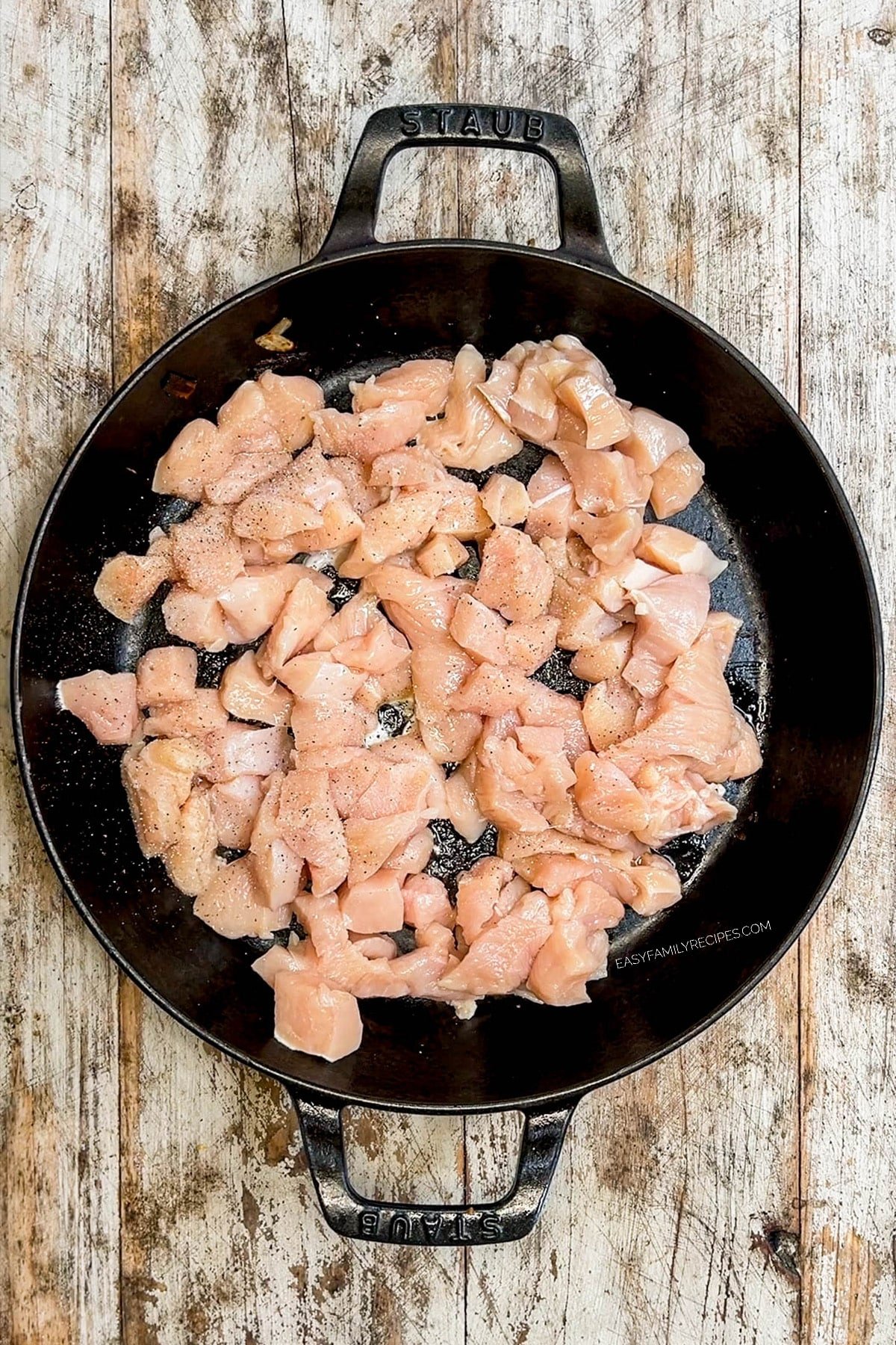 Chicken being cooked in a black skillet for hibachi bowls.