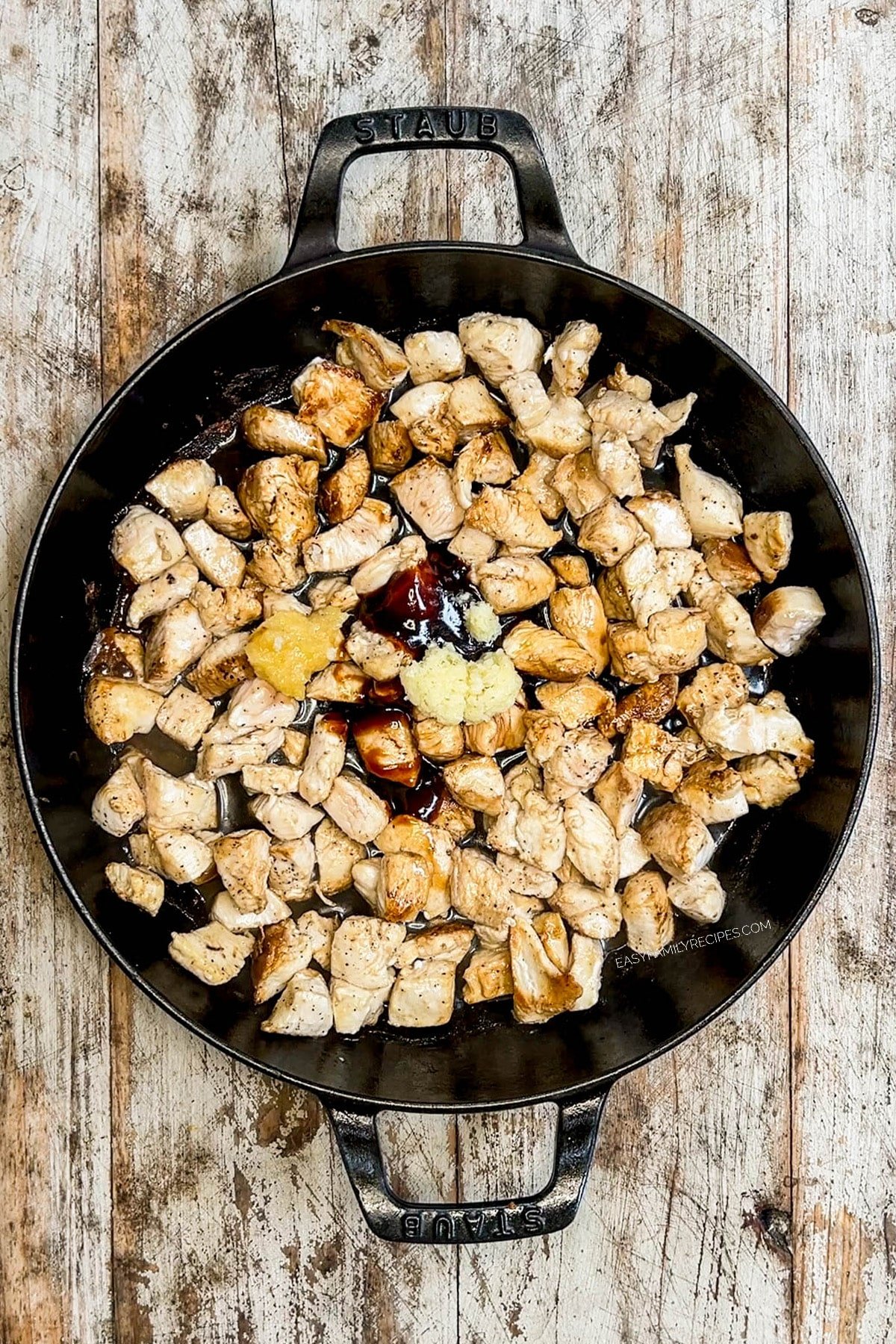 Chicken is cooked in a black skillet for hibachi chicken bowls.