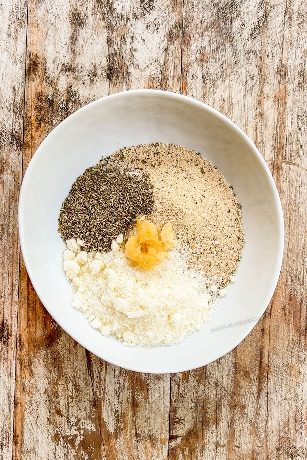 A white bowl full of ingredients for the breading for baked chicken cutlets.