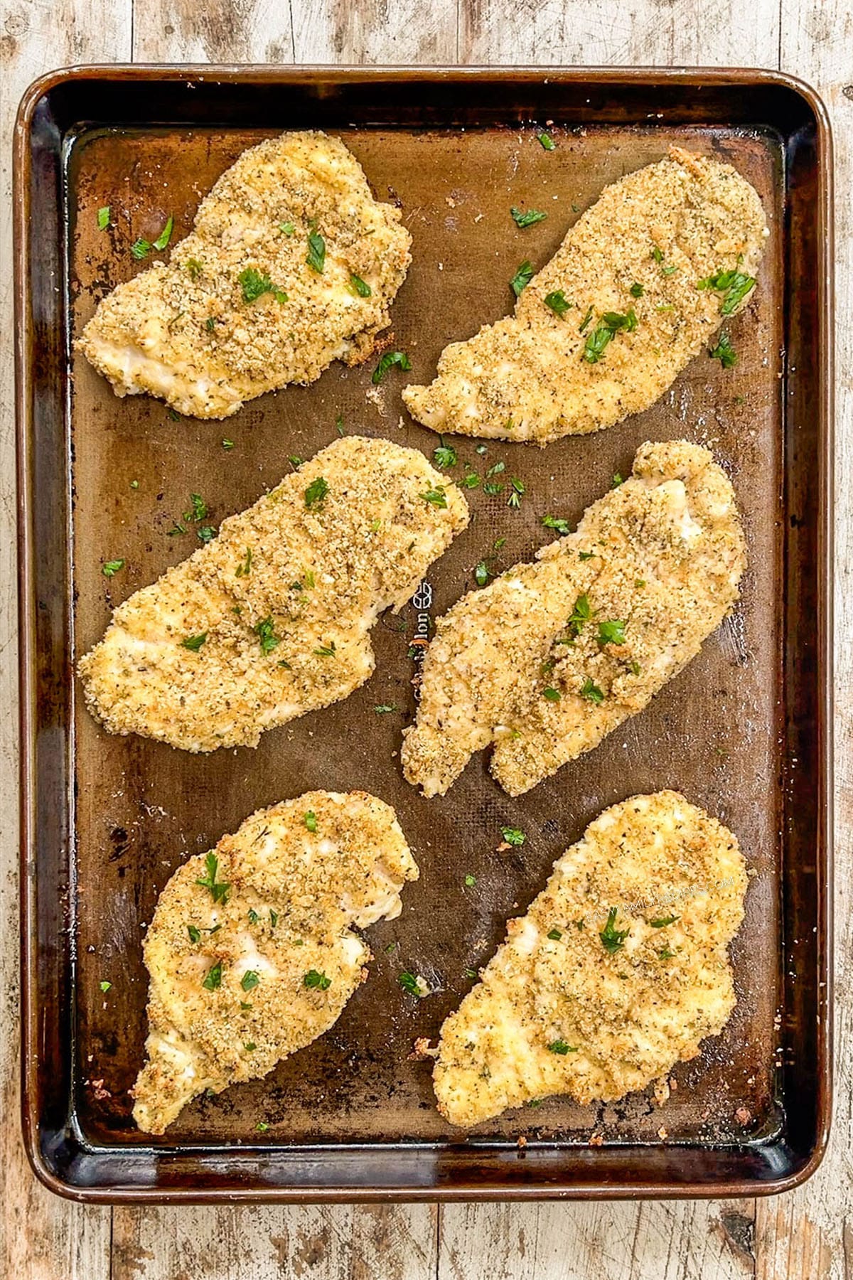 Baked breaded chicken on a baking sheet.