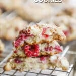 raspberry cheesecake cookie halves stacked onto a cooling rack.